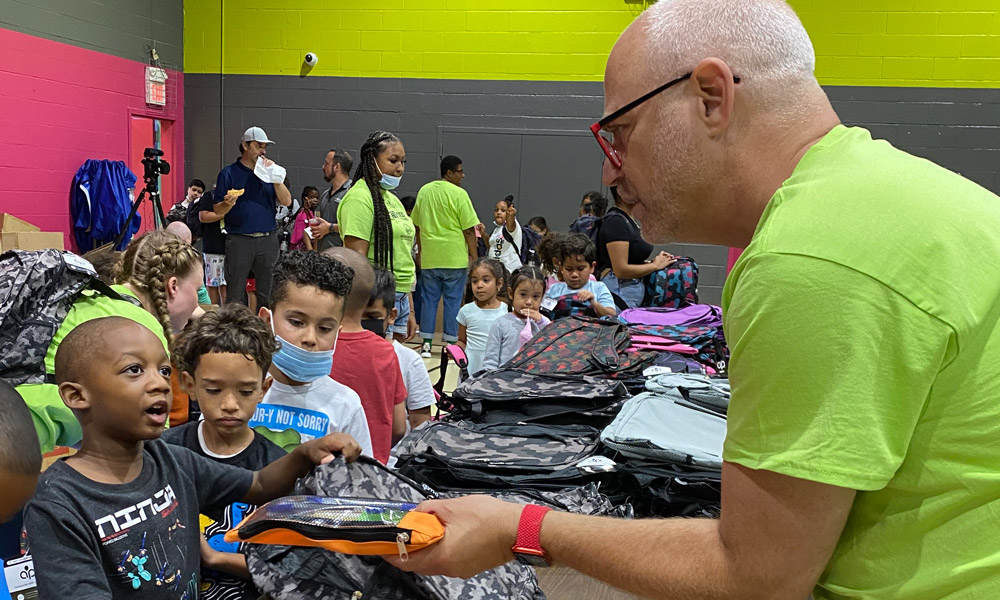 Infolinks CEO Bob Regular helps a young boy from Paterson, NJ pick out a pencil case.